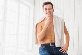 Smiling man with a towel draped over his shoulder, sitting in a bright, wellness-focused environment, reflecting the health and rejuvenation themes of CHS Med Spa's services.