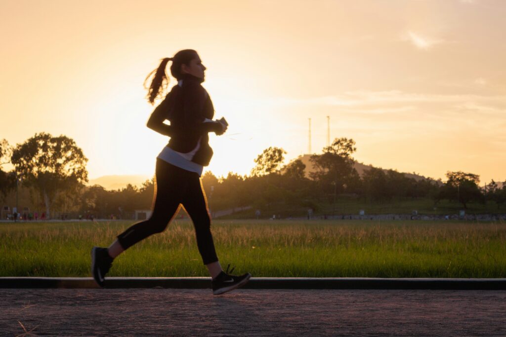 Woman jogging in a park at sunset, symbolizing vitality and energy, relevant to BHRT and wellness at CHS MedSpa.