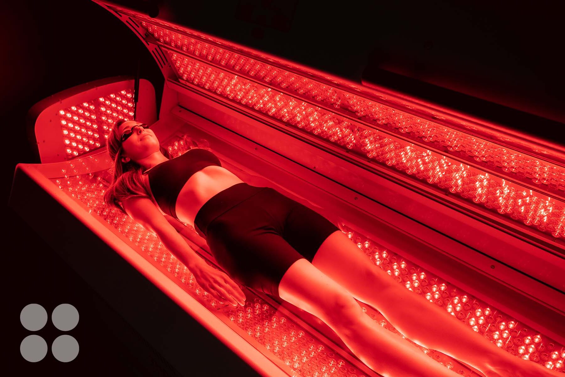 Woman receiving Red Light Therapy treatment in a medical spa setting, surrounded by red LED lights, promoting skin health and wellness.